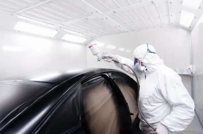 pistolet do natrysku czarnym lakierem w lakierni samochodowej